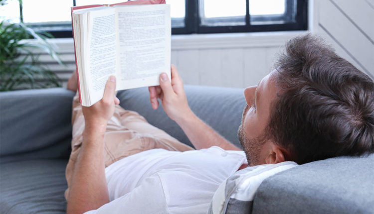 Senyor llegint estirat en un sofà