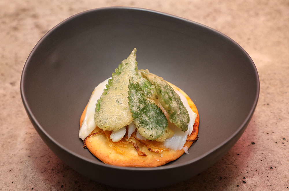 Coca de recapte amb bacallà confitat, ceba tendra i tempura d'ortigues