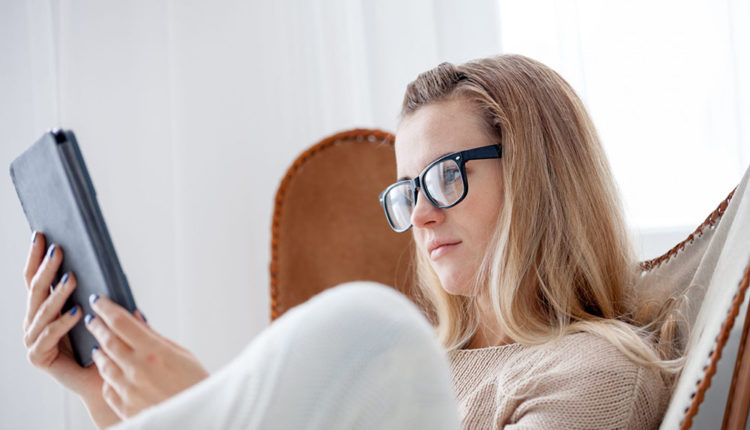young-woman-in-glasses-reading-ebook-using-digital-FYRUGJL-scaled